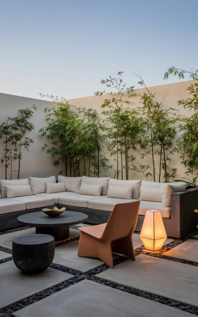 Modern outdoor lounge, minimal design, low-profile sectional, concrete pavers, matte black planters, sculptural chair, statement lantern, no humans, clean lines, bold textures, open sky, minimalism, neutral tones, calm atmosphere